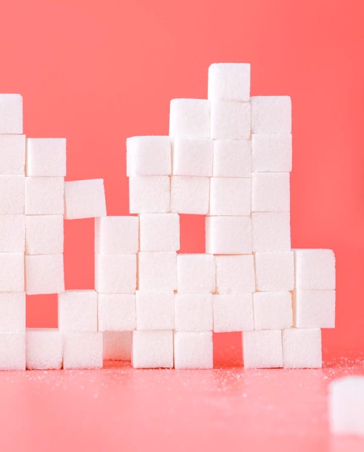 stacked sugar cubes against a pink background