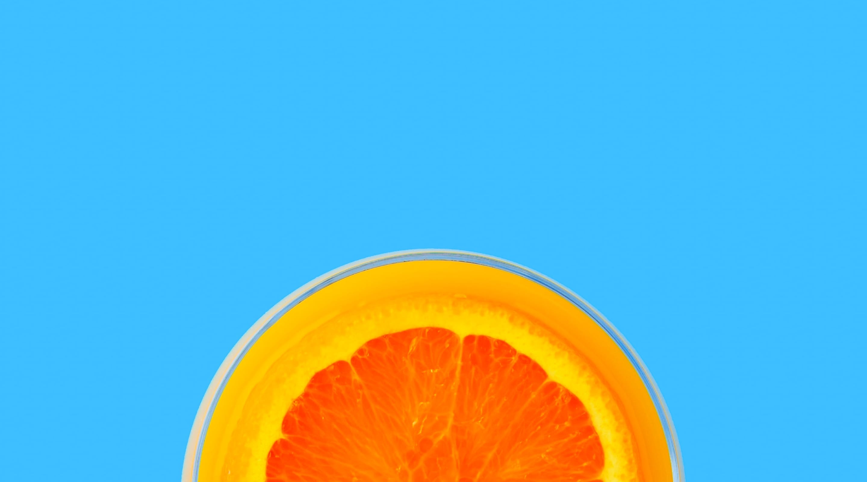 Half slice of an orange against a cyan-colored background