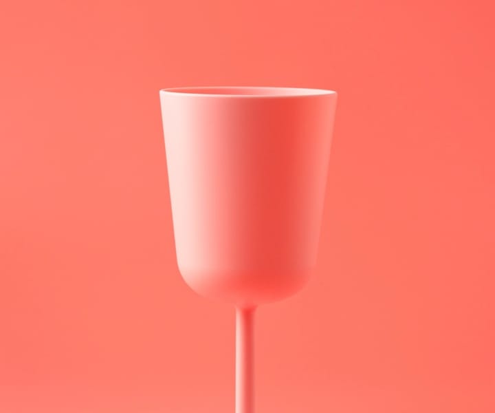 A pale red plastic cup against an almost similar pale red background